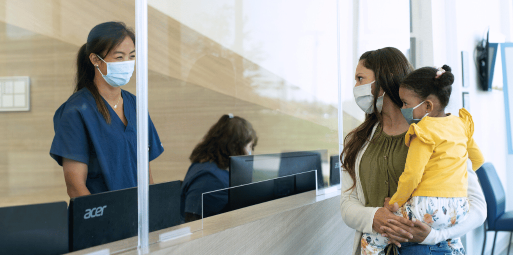 receptionist and mother and daughter patient checking into Legacy ER & Urgent Care